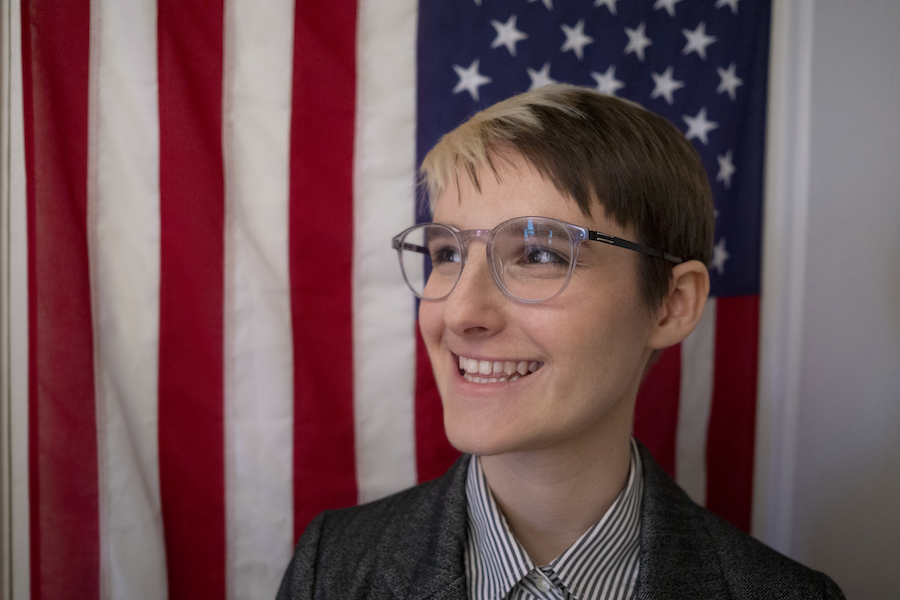 B dons glasses and smiles broadly with the backdrop of the American flag