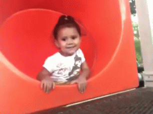 Small child waves goodbye before disappearing down a tunnel slide